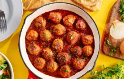 Albóndigas caseras en salsa putanesca servidas en una sartén con cebollas y cilantro Albóndigas caseras en salsa putanesca servidas en una sartén con cebollas y cilantro