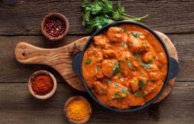Butter Chicken en estilo rústico con especias aromáticas Butter Chicken con cilantro y acompañado de especias sobre tabla de madera
