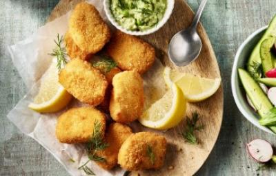 Trozos de chicharrón de pollo crujiente servidos con salsa verde, rodajas de limón y ensalada fresca