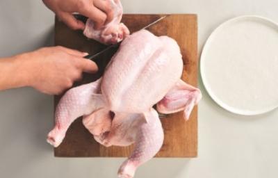 Corte de la carcasa de pollo sobre una tabla de madera, ideal para usar en caldos de hueso de pollo