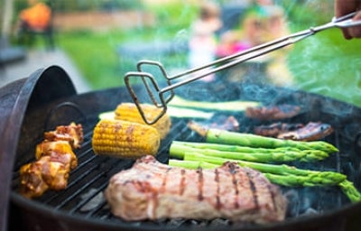 Filete de carne asada con choclo, chorizo y vegetales sobre parrilla volcánica.