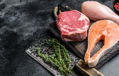Hay varios tipos de carne magra, desde el filete de salmón hasta la pechuga de pollo. Distintos tipos de carne magra en la mesa listos para asar