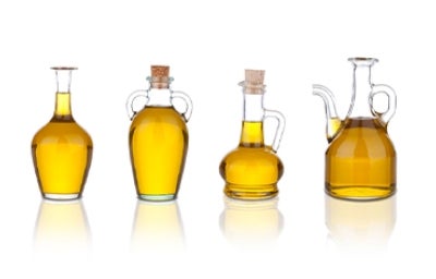 Cuatro tipos de aceite de cocina en recipientes de vidrios distintos.