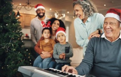 Navidad: una familia feliz y un anciano al piano en el salón, celebrando con canciones de navidad.