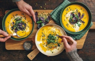 Sopa cremosa de calabaza asada vegana sobre fondo de madera