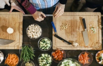 Tabla de cortar de madera con cuencos y verduras, inocuidad que es.