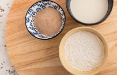 Almidón de yuca, harina y leche. Cuenco decorativo de bambú y negro. Plato giratorio de madera. Vista superior.