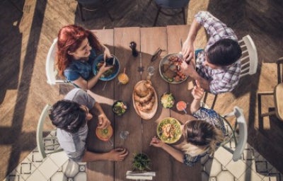 Vista superior de jóvenes disfrutando de un almuerzo con todos los grupos alimenticios en un restaurante.