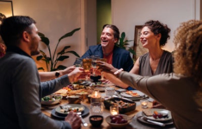 Amigos brindando con una copa de vino durante una cena.