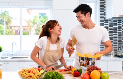 Pareja cocinando pasta con un cazo.