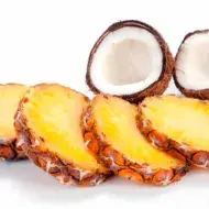 Tajadas de piña y un coco partido por la mitad, dos frutas tropicales
