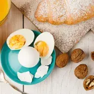 Huevos cocidos, acompañados por jugo de naranja y un croissant.