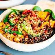 Granos, semillas, frutas y verduras en un plato de comida vegetariana.