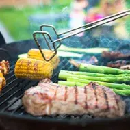 Asado de carne y vegetales, con pinzas para darles vuelta, un utensilio muy importante.