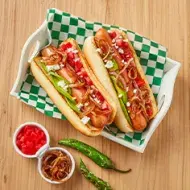 Plato con hot dogs, cebollas caramelizadas, tomates y chiles 