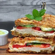 Pan panini relleno de jamón, tomate y albahaca, acompañado con salsa Pan panini relleno de jamón, tomate y albahaca, acompañado con salsa