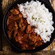 Carne en cuadros y arroz blanco en una sartén de hierro.