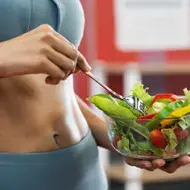 Una mujer con una ensalada después de salir a hacer ejercicio en una rutina de vida activa