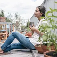 Una mujer con un vaso y un plato de comida aprovechando un buen descanso.