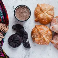 Panes dulces mexicanos tradicionales acompañados de chocolate caliente y un molinillo