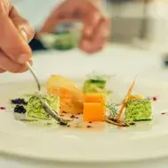 Una persona emplatando con una cuchara una comida con caviar