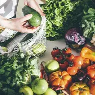 Una persona sacando productos orgánicos, frutas y verduras de una bolsa