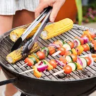 Asador con vegetales y pinzas de cocina  