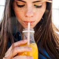 Mujer bebiendo un refrescante jugo de zanahoria con limón