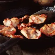 Deliciosa panceta cortada siendo fritada en un sartén