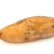 Un camote sin pelar en fondo blanco.