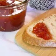 Rebanada de pan con mermelada casera de fresa, recipiente de vidrio sobre tabla