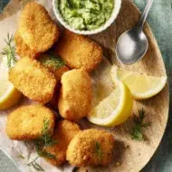 Trozos de chicharrón de pollo crujiente servidos con salsa verde, rodajas de limón y ensalada fresca