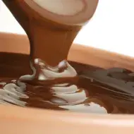 Crema de avellanas, topping habitual en las obleas con fruta. Espesa crema de avellanas vertiéndose en un bowl.