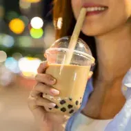Mujer disfrutando de una bebida complementada con perlas de tapioca.