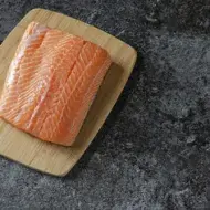 Filete de salmón fresco, uno de los tipos de salmón más usados Filete de salmón fresco sobre tabla de madera