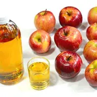 Vinagre de sidra de manzana al lado de manzanas.