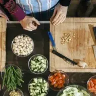 Tabla de cortar de madera con cuencos y verduras, inocuidad que es.