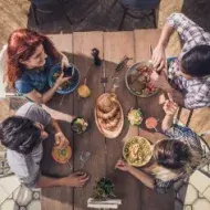 Vista superior de jóvenes disfrutando de un almuerzo con todos los grupos alimenticios en un restaurante.