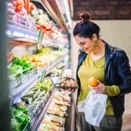 Mujer comprando níspero en el supermercado.