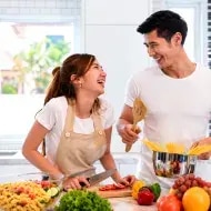 Pareja cocinando pasta con un cazo.